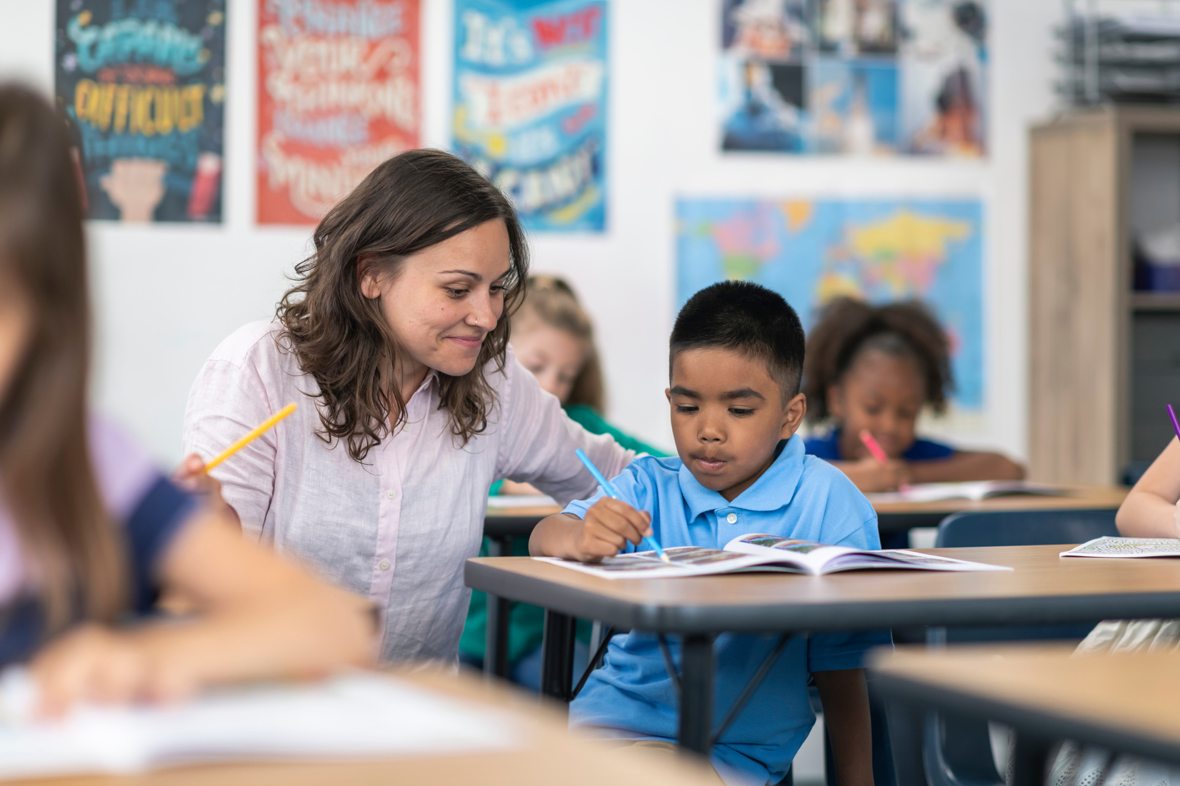 Teacher assists elementary student with assignment